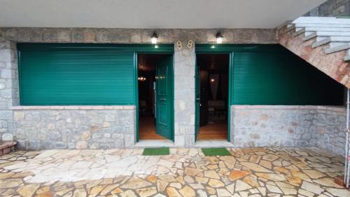 ein Gebäude mit grünen Türen und einer Steinmauer in der Unterkunft Traditional cozy apartments in Livadi Parnassos in Kalívia