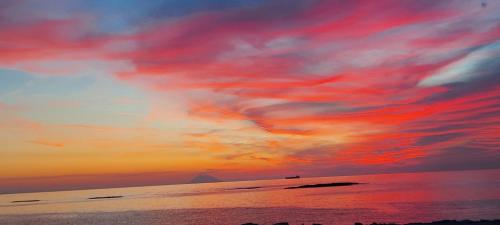a sunset on the beach with red clouds at Clausis in Parghelia