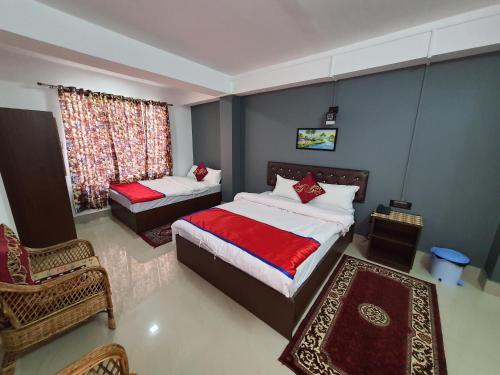 een slaapkamer met twee bedden en een stoel en een raam bij Chunnihome in Gangtok