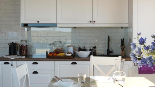 a kitchen with white cabinets and a table with a bowl of fruit at AURA Centrum Wypoczynkowo-Rekreacyjne in Sejny