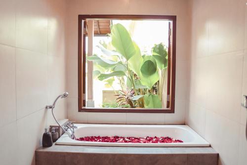 a bath tub in a bathroom with a window at Abinawa Hill in Lovina