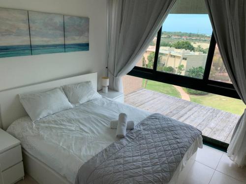 a white bed in a bedroom with a large window at Caesarea Magic in Caesarea