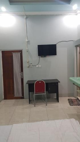a desk with a red chair and a television on a wall at Rezka Roomz Syari'ah in Ende