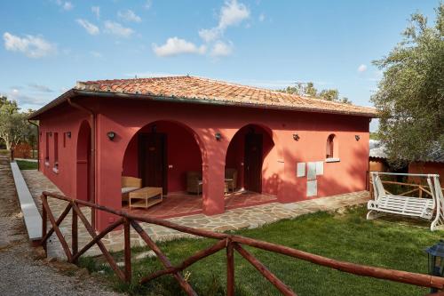 ein rotes Haus mit einem Zaun davor in der Unterkunft Podere Somboli in Monte San Savino