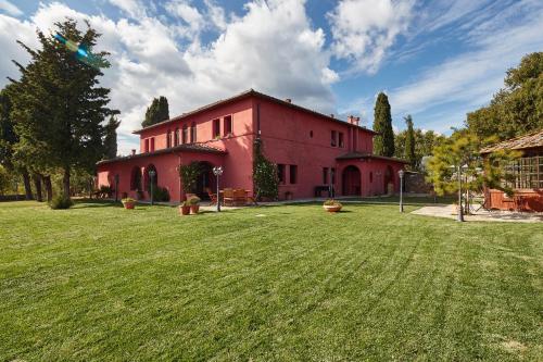 ein rotes Gebäude mit einem großen Hof davor in der Unterkunft Podere Somboli in Monte San Savino