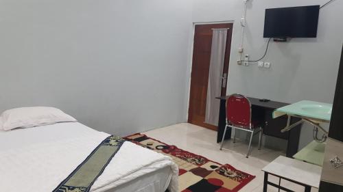 a bedroom with a bed and a desk and a table at Rezka Roomz Syari'ah in Ende