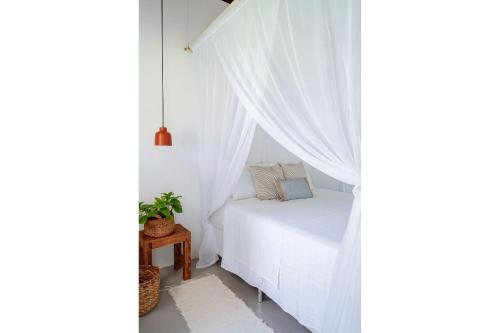 a bedroom with a bed with white curtains at Orixás Residence in Morro de São Paulo