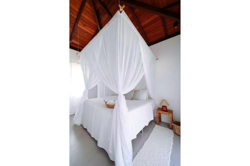 a bedroom with a bed with white mosquito nets at Orixás Residence in Morro de São Paulo
