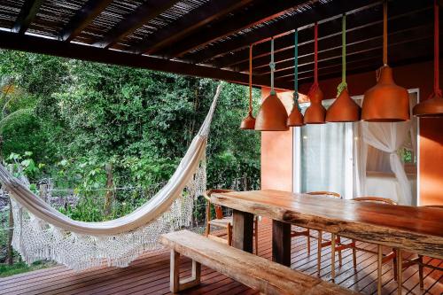 a hammock on a deck with a table and chairs at Orixás Residence in Morro de São Paulo