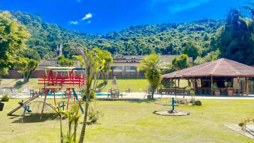 un parque con parque infantil, un edificio y árboles en Hotel Nascentes da Serra en Poços de Caldas