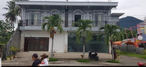 a man and woman standing in front of a house at Rezka Roomz Syari'ah in Ende