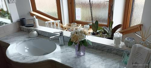 a bathroom sink with a vase of flowers on a counter at Outlander Boutique B&B ONLY ADULT Suite in Cruden Bay