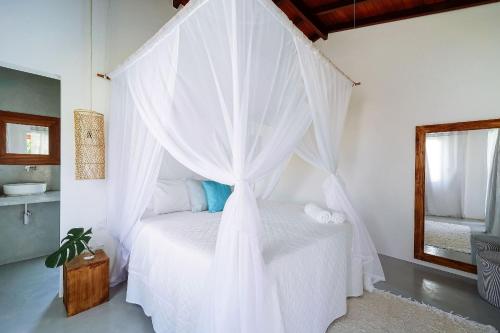 a bedroom with a white bed with a canopy at Orixás Residence in Morro de São Paulo
