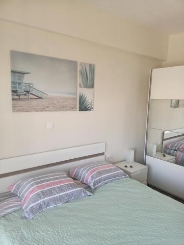 a bed with striped pillows in a white bedroom at Paparoúna 5 min from beach in Nikiti