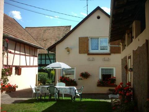 a patio with a table and chairs and an umbrella at Gîte Le Jardin in Geispolsheim