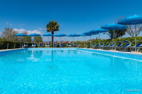 una gran piscina con sombrillas y sillas azules en Albergo Bagner, en Sirmione