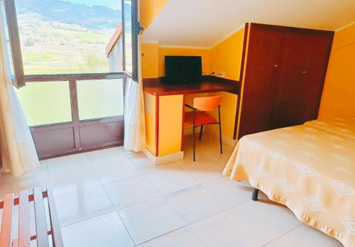 a bedroom with a desk and a bed and a window at Hotel Alameda in Villaviciosa