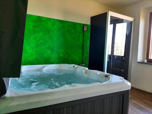 baño con bañera con pared verde en Villa Sofia Eden & Spa, en Gaiole in Chianti