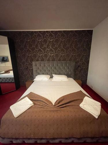 a bedroom with a large bed with two towels on it at Hotel Mon Caprice in Bucharest