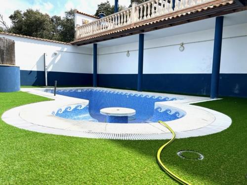 a swimming pool with a hose in the grass at Paradise in Aldea del Fresno