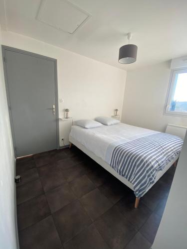 een witte slaapkamer met een bed en een raam bij Appartement T2 bis, 200m de la mer, très calme in Camiers