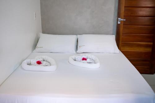 a bed with two white pillows with flowers on it at Acoara Beco Doce in Jericoacoara