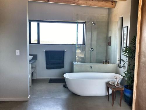 un bagno con ampia vasca bianca e lavandino di A Real Gem in Cape St Francis a Cape St Francis