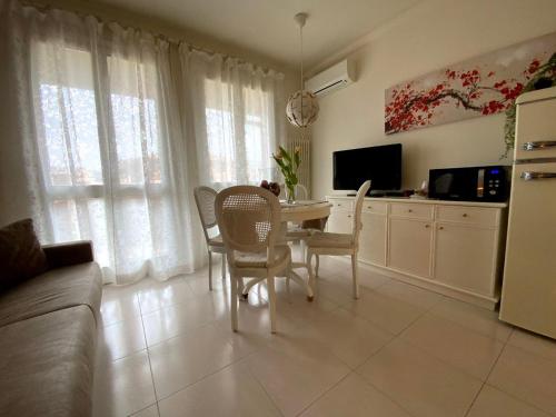 un soggiorno con tavolo, sedie e TV di Elena Apartment Residence a Bardolino