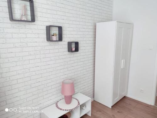 a room with a white brick wall with a pink stool at Apartament Anastazja in Koszalin