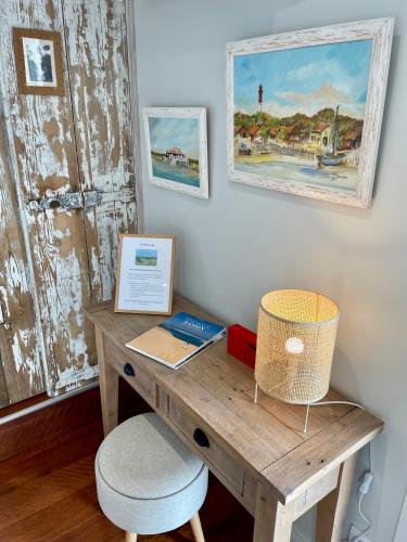 un bureau en bois avec une chaise à côté d'un mur dans l'établissement Au Phare du Cap, à Cap-Ferret
