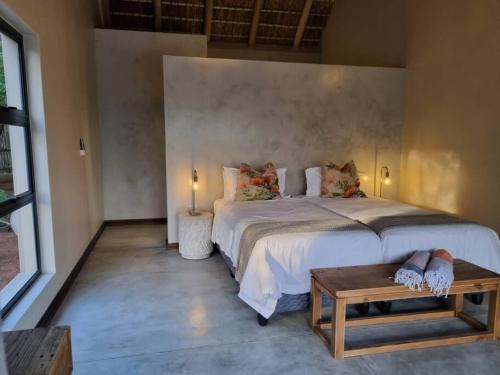a bedroom with a large bed and a table at UmnDeni Africa in Hoedspruit