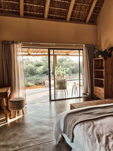 a bedroom with a bed and a view of a patio at UmnDeni Africa in Hoedspruit