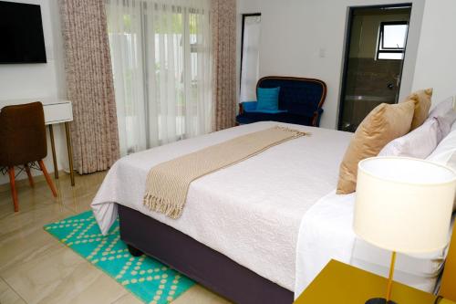 ein Schlafzimmer mit einem Bett und einem blauen Stuhl in der Unterkunft Getty's Bed and Breakfast in Mabele-a-podi
