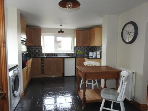 a kitchen with a table and a clock on the wall at Butland House in Pembrokeshire