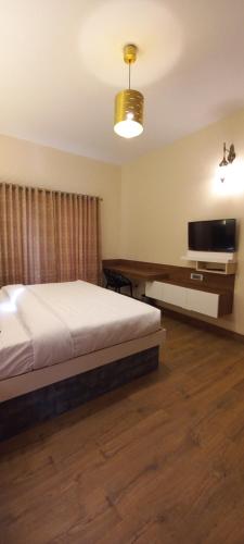 a bedroom with a bed and a flat screen tv at Salora Kodai in Kodaikānāl
