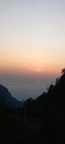 a sunset over the ocean with the sun in the distance at Salora Kodai in Kodaikānāl