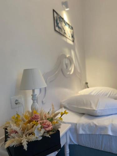 a bed with a table with a lamp and flowers on it at Blue Sea Hotel in Kamari