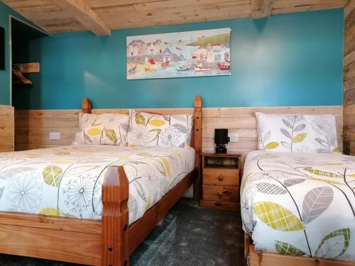 two beds in a bedroom with blue walls at Pensalda Guest House in Newquay