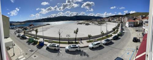 a parking lot with cars parked next to a beach at Rompeolas in Laxe