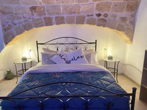 a bedroom with a blue bed with a stone wall at La casa dell'angelo in Monopoli
