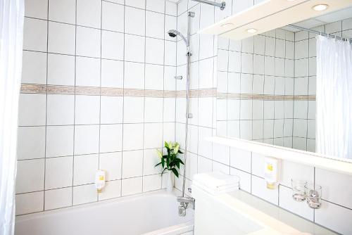 a white tiled bathroom with a tub and a shower at Hotel Albrechtshof Gohrisch in Kurort Gohrisch