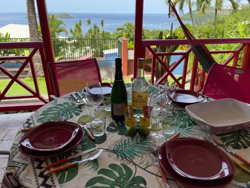 una mesa con copas y botellas de vino en el balcón en Le Nid Tropical, en Bouillante