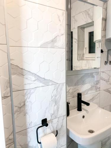 a white bathroom with a sink and a shower at Domki za Wyspą in Chmielów