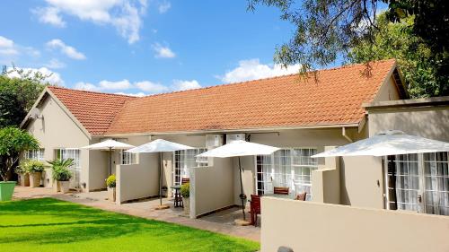 a building with white umbrellas in the courtyard at Khayamanzi Guesthouse in Hartbeespoort