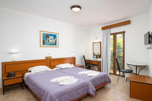 a bedroom with a large bed and a desk and chair at Emily Hotel in Samos