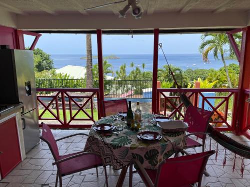 a dining room with a table and chairs and the ocean at Le Nid Tropical in Bouillante