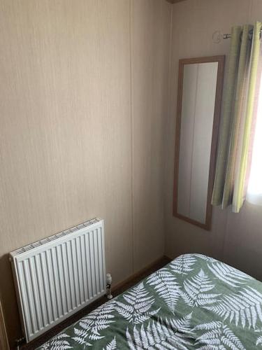 a bedroom with a bed and a mirror and a window at A 'Small' Hideaway in Pakefield