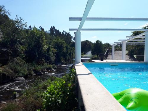 a swimming pool with a river next to it at Dream corner by waterfalls, 20 min to Oporto in Parada