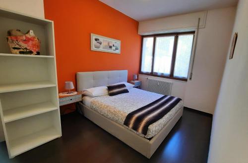 ティラーノにあるLucini Ai Porticiのオレンジ色の壁のベッドルーム1室(ベッド1台付)