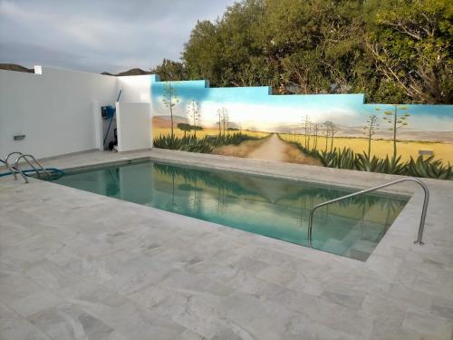 - une fresque murale sur le côté d'un bâtiment blanc avec une piscine dans l'établissement Loft con piscina comunitaria, à Las Negras